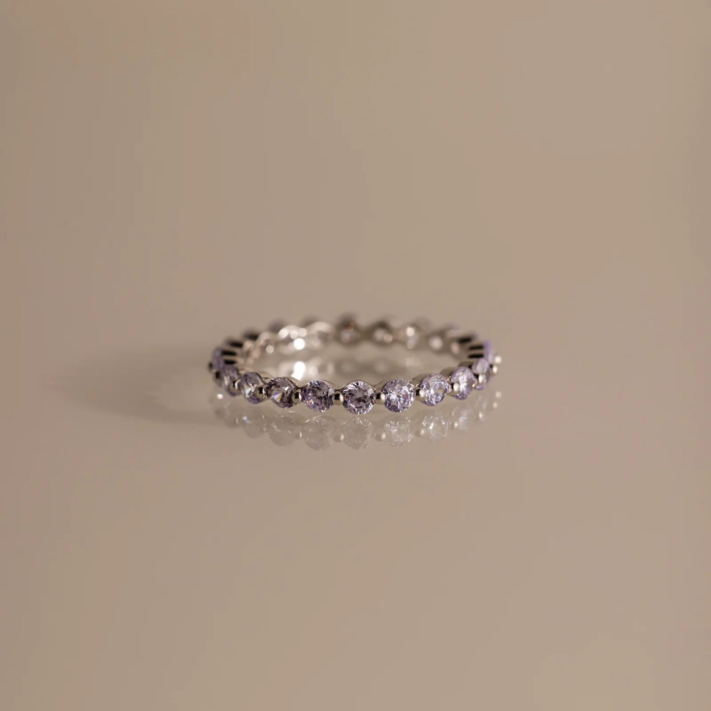 Silver ring with small diamonds on a beige background