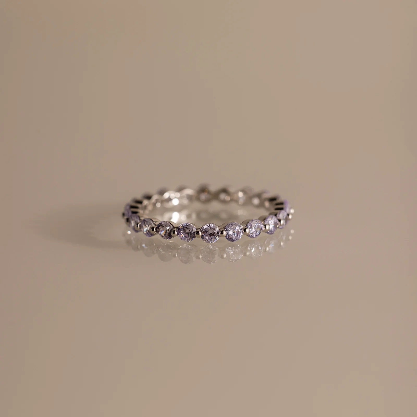 Silver ring with small diamonds on a beige background