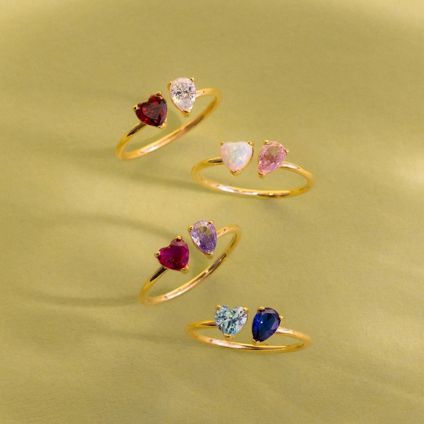 Set of gold rings with heart-shaped gemstones on a green background