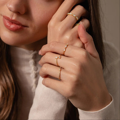 Woman wearing multiple gold rings on a neutral background