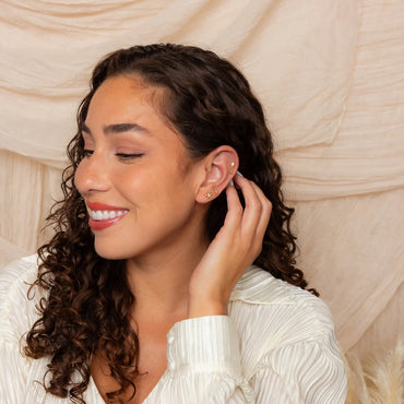 Woman wearing gold earrings against a beige curtain background