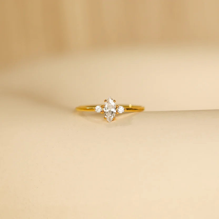 Gold ring with a diamond on a beige background