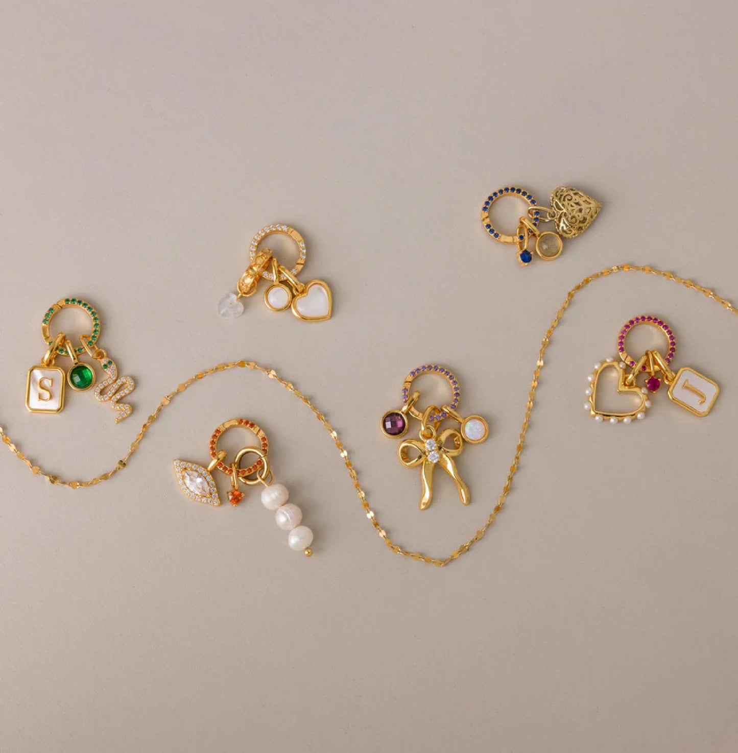Gold jewelry set with various charms on a beige background
