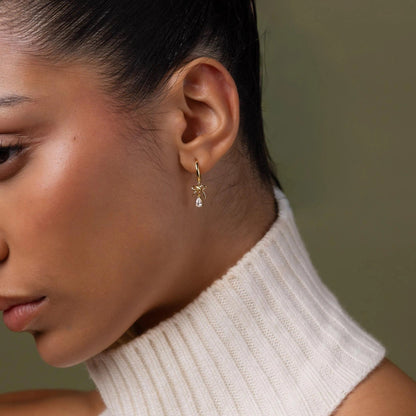 Close-up of a woman wearing a gold earring with a green background