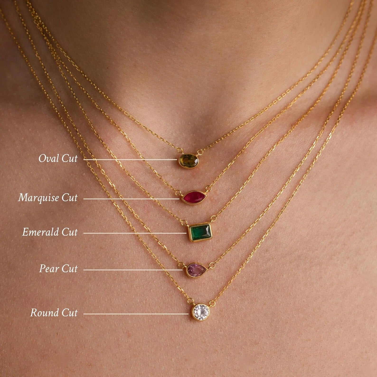 Gold necklaces with different cut gemstones on a skin background