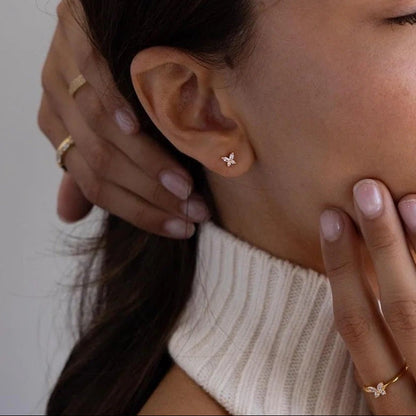 Woman wearing gold earrings and rings with a neutral background