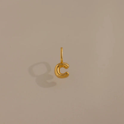 Gold 'C' shaped pendant on a beige background