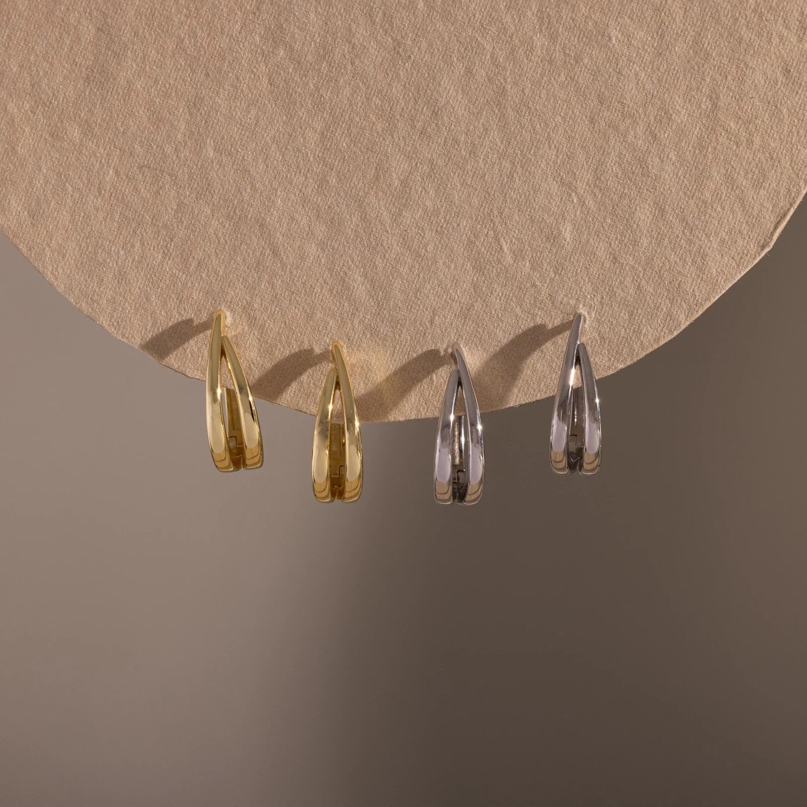 Four teardrop-shaped earrings on a brown background