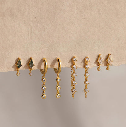 Set of gold and gemstone earrings on a beige background