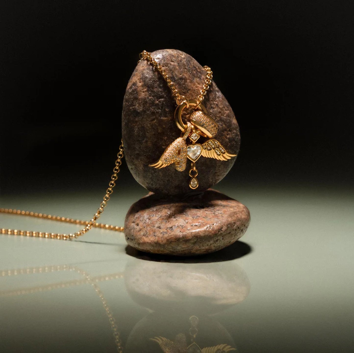 Gold necklace with a pendant on a reflective surface with a dark background
