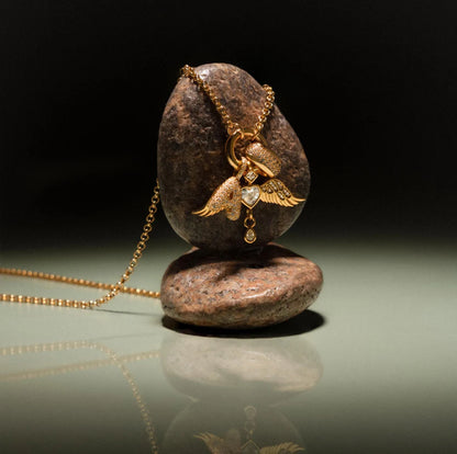 Gold necklace with a pendant on a reflective surface with a dark background