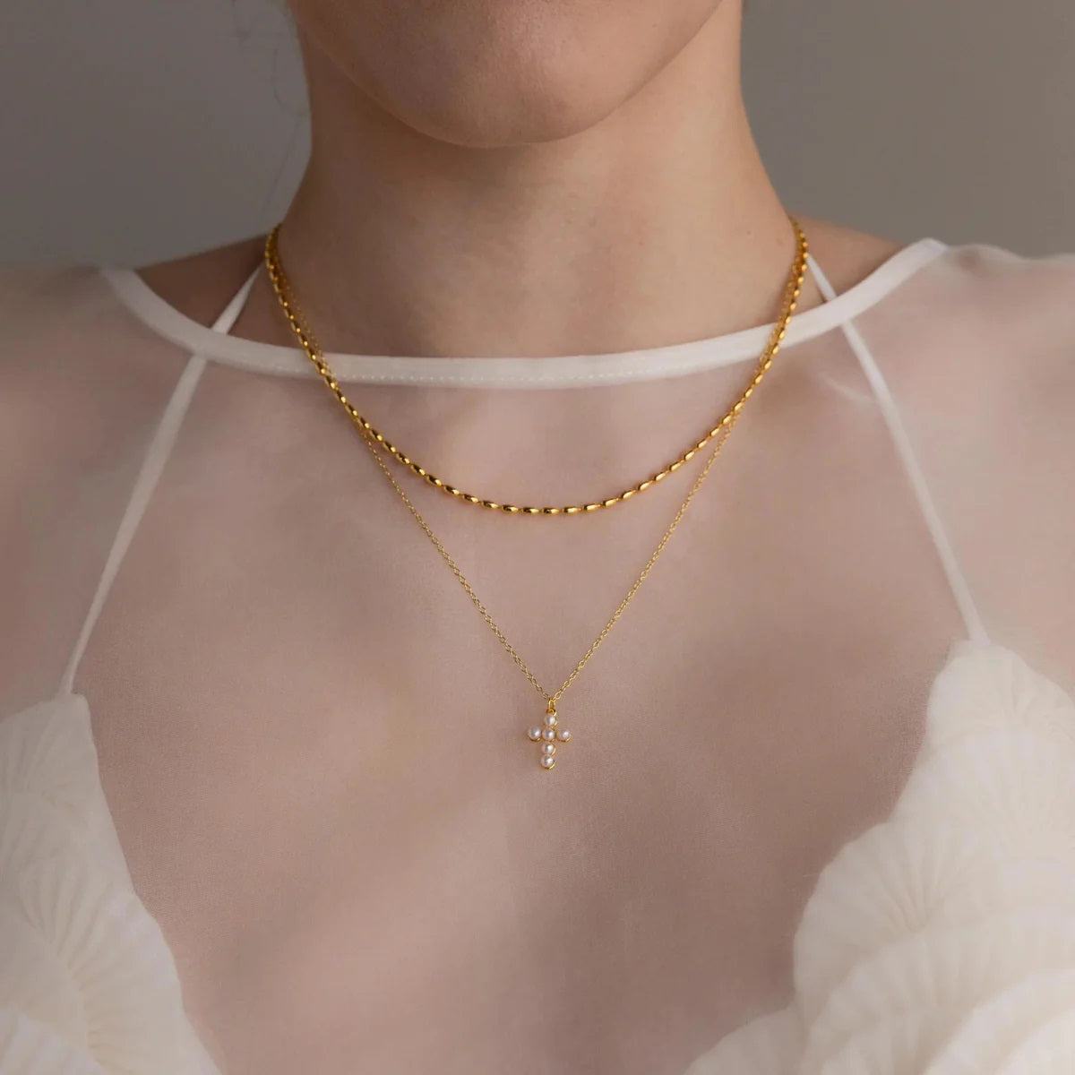 Gold necklace with a small pendant worn by a person in a white top.