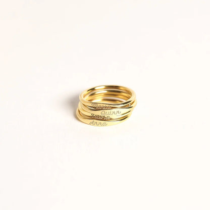 Stack of gold rings with engraved names on a white background