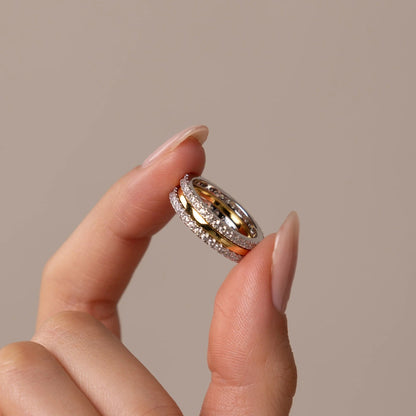Hand holding a diamond ring against a beige background
