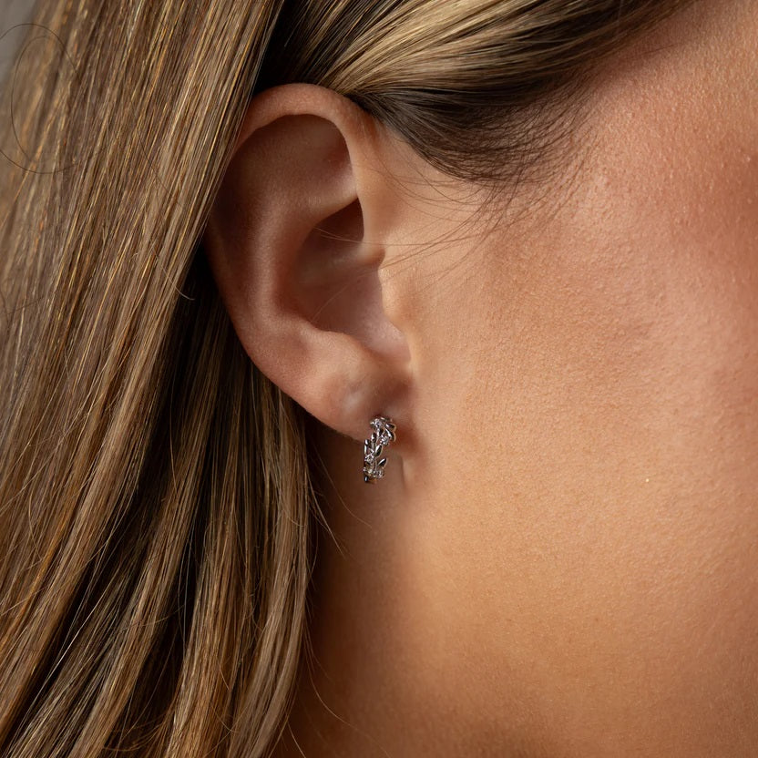 Close-up of an ear wearing a small earring with hair partially covering the frame.