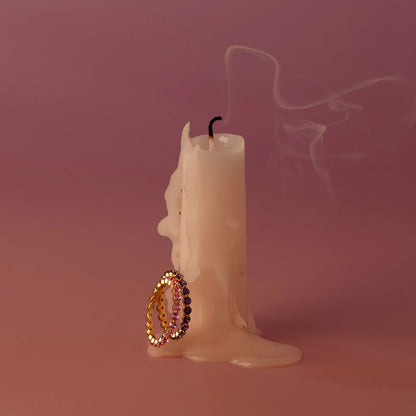 Candle with a decorative earring on a pink background