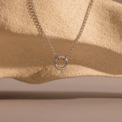Silver necklace with a circular pendant on a beige surface