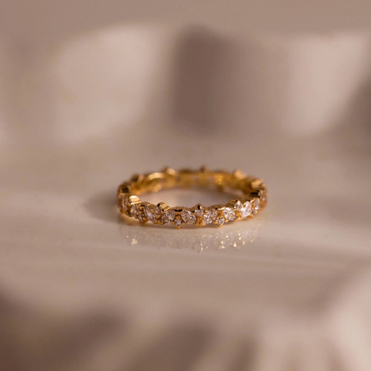 Gold ring with diamonds on a beige fabric background