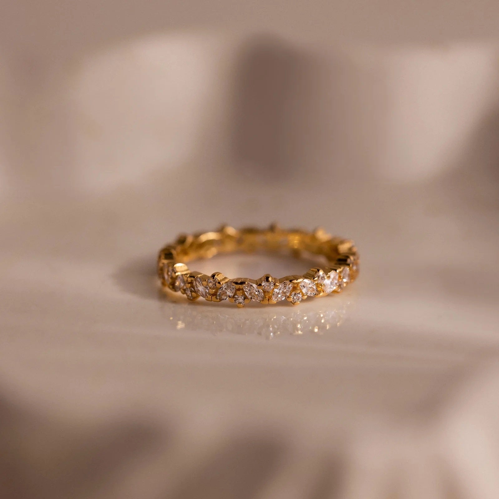 Gold ring with diamonds on a beige fabric background