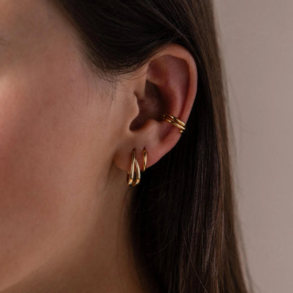 Close-up of a person wearing gold earrings and a gold hoop earring.