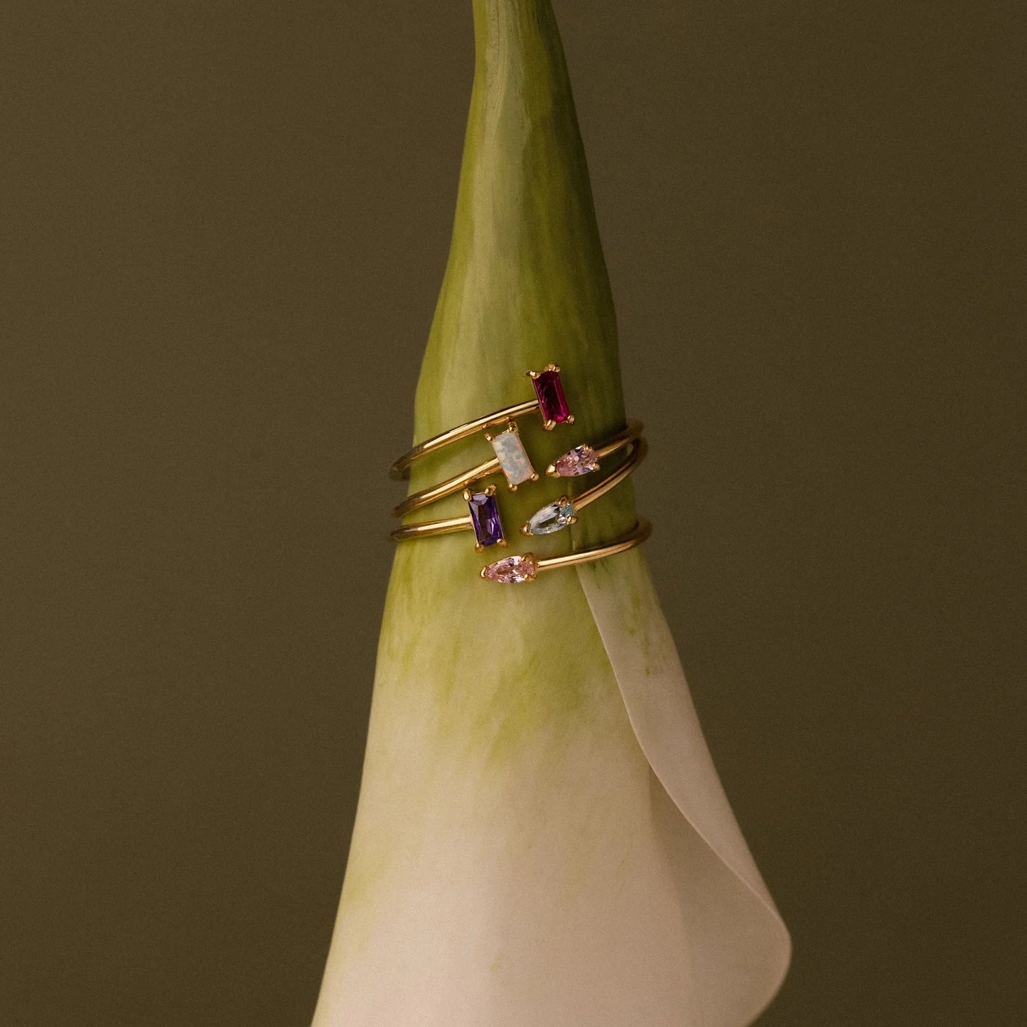 Gold ring with gemstones on a green flower against a brown background