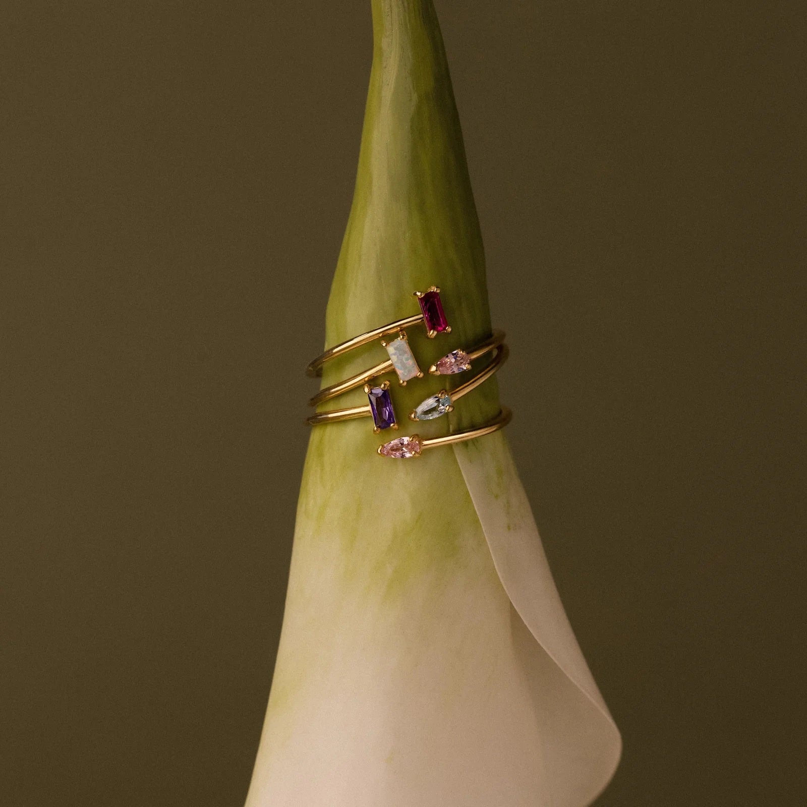 Gold ring with gemstones on a green flower against a brown background