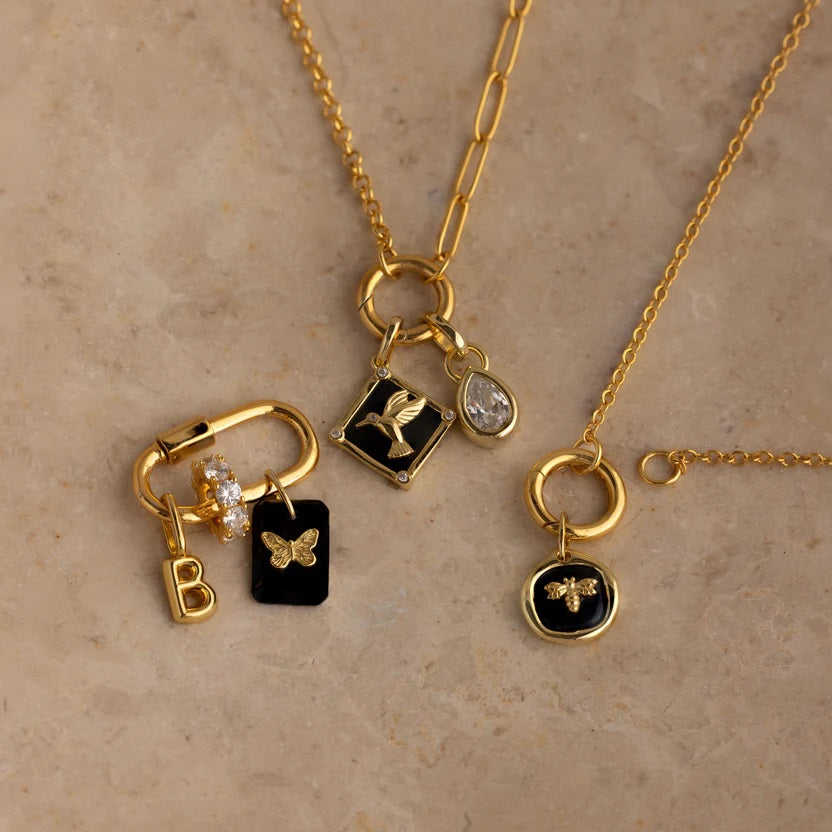 Gold necklaces with various charms on a beige background