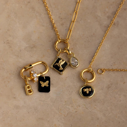 Gold necklaces with various charms on a beige background