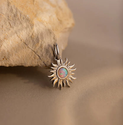 Sun-shaped pendant with a central gemstone on a stone background