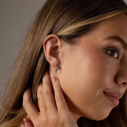 Close-up of a woman wearing a diamond earring with a neutral background