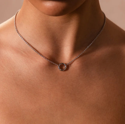 Necklace with a circular pendant on a person's neck against a neutral background