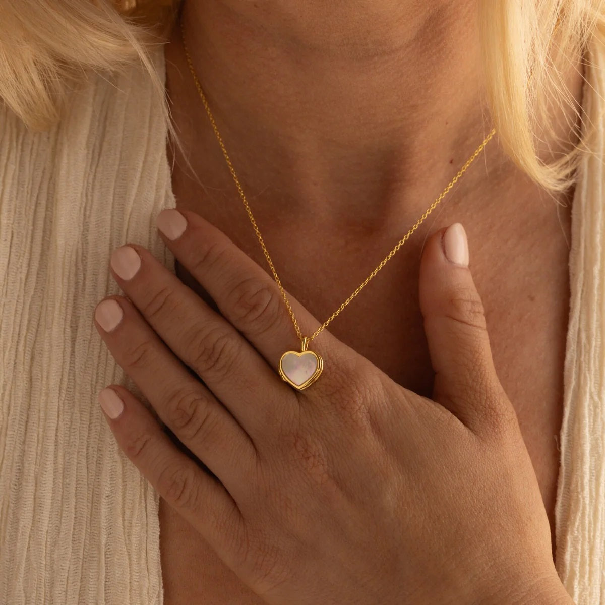 Gold necklace with a heart-shaped pendant worn by a person