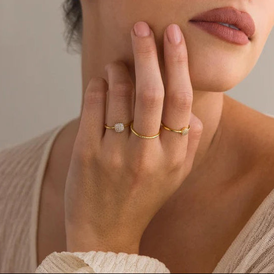 Woman wearing gold rings on a neutral background