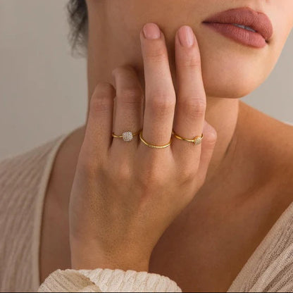 Woman wearing gold rings on a neutral background