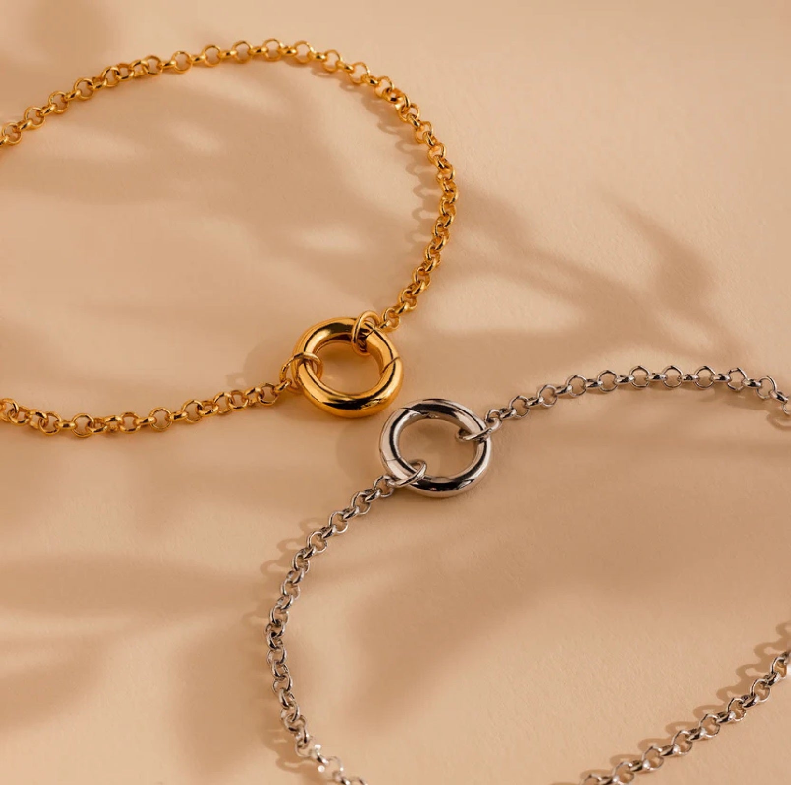 Gold and silver chain necklaces on a beige background