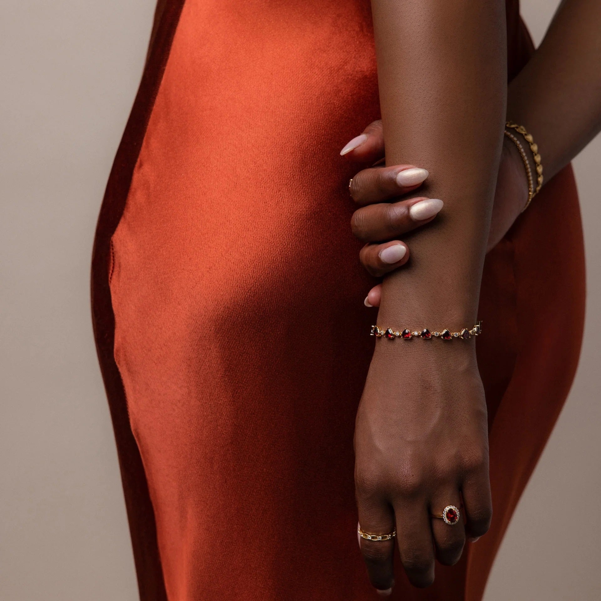 Close-up of a person's arm with jewelry against a neutral background