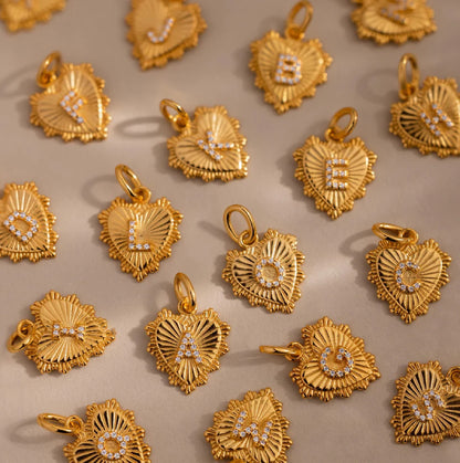 Gold heart-shaped pendants with letters on a beige background