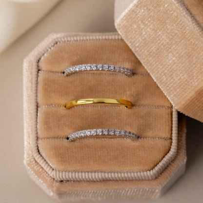 Three diamond rings on a beige velvet jewelry box with a neutral background