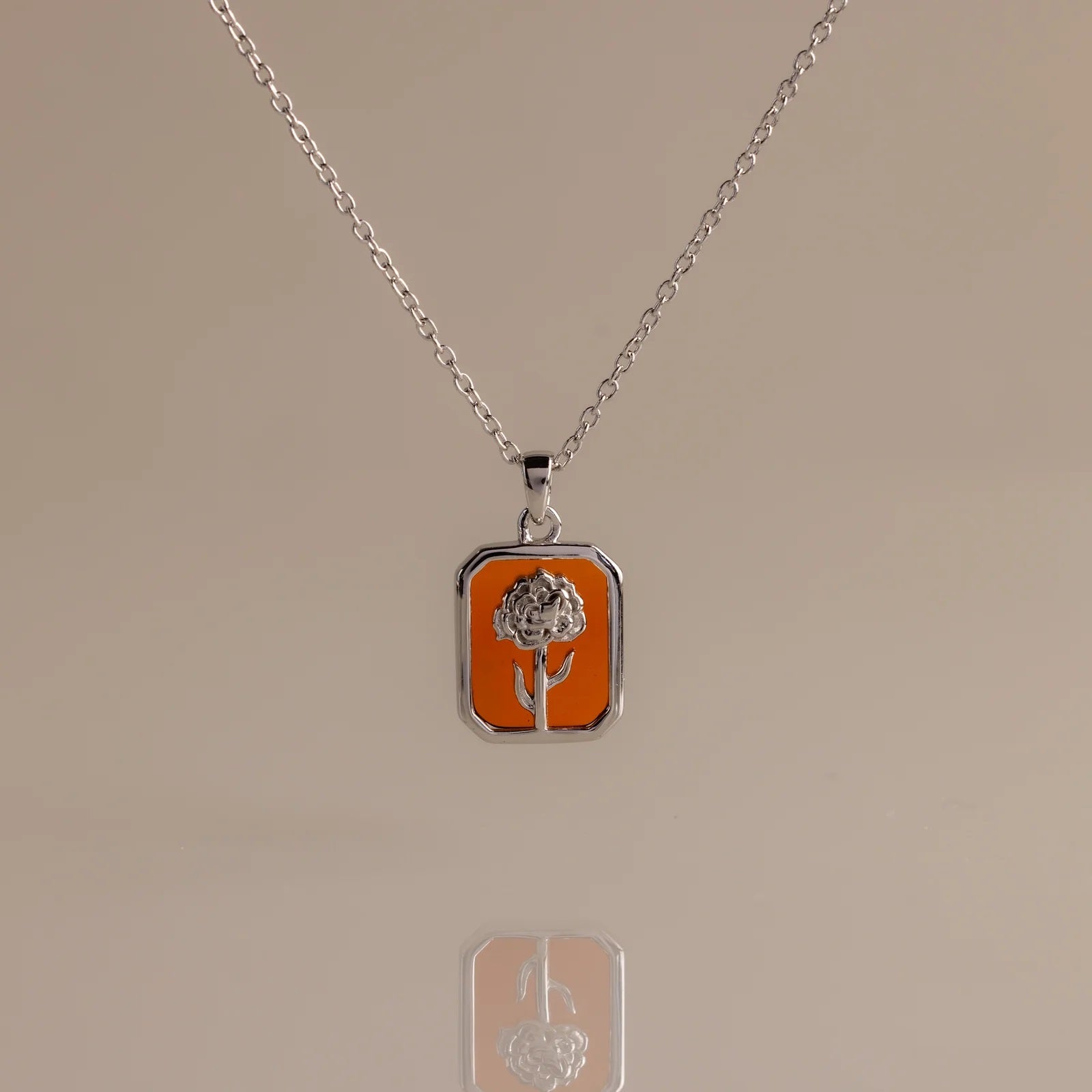 Gold necklace with a rose pendant on a beige background