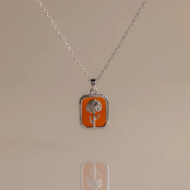 Gold necklace with a rose pendant on a beige background
