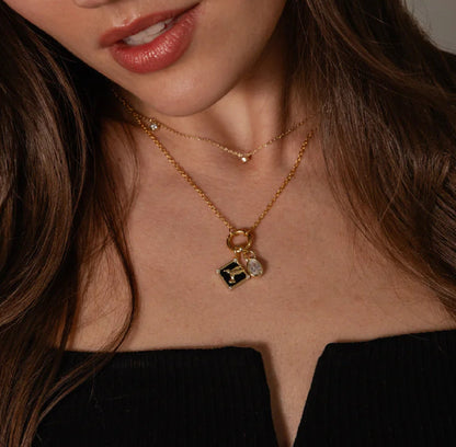 Woman wearing a gold necklace with a pendant against a neutral background