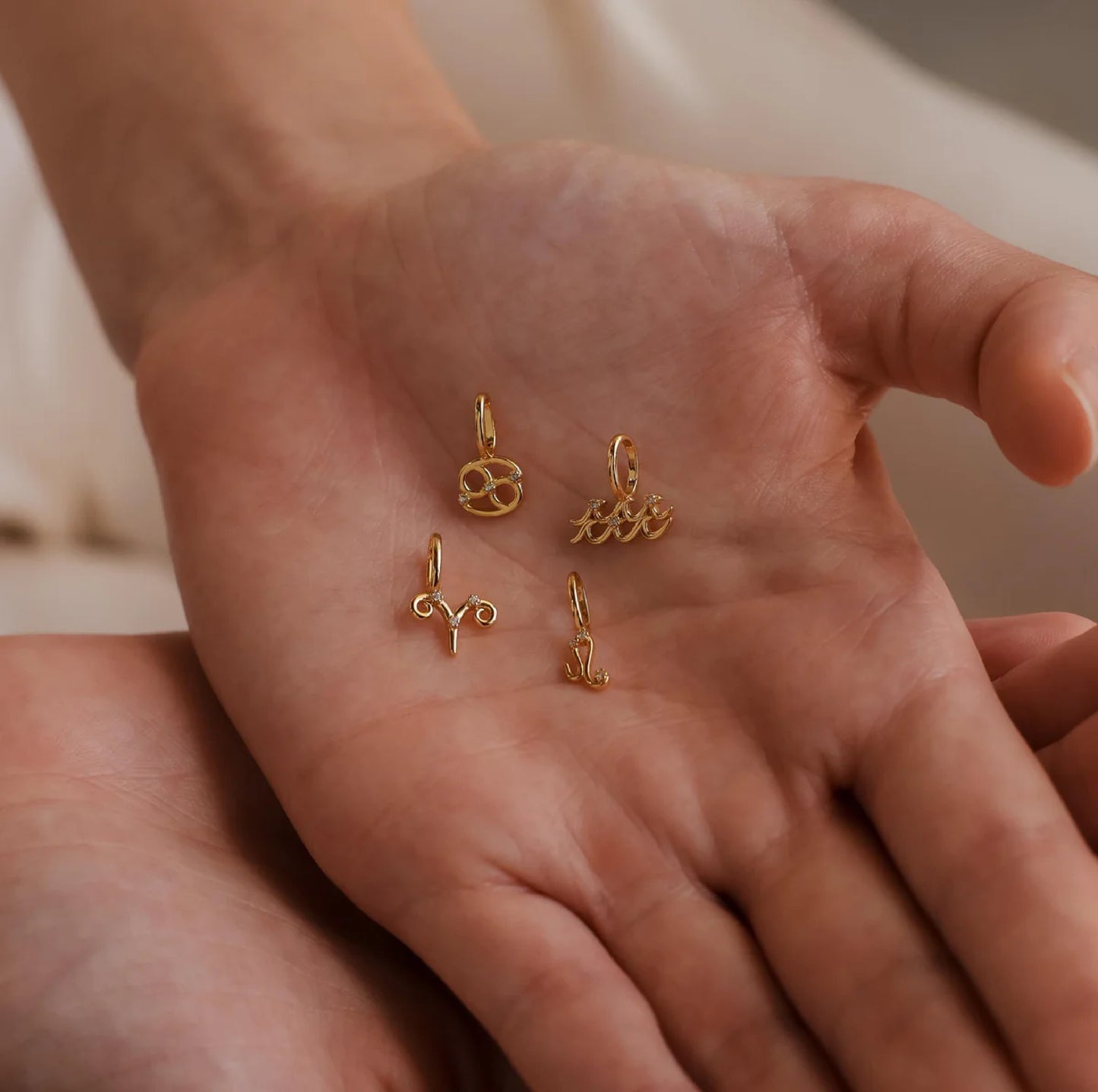 Gold jewelry charms on a person's palm