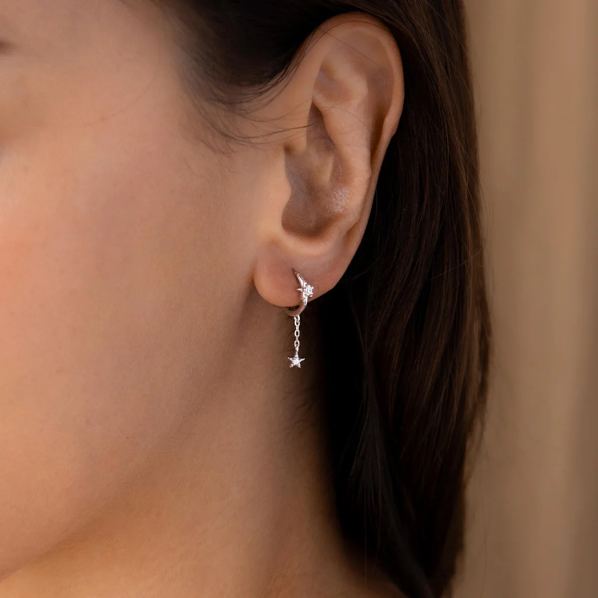 Close-up of an ear wearing a star-shaped earring with a blurred background