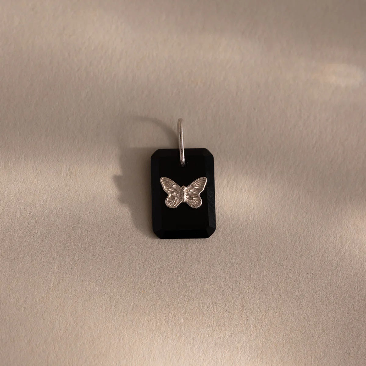Butterfly pendant on a black card against a beige background