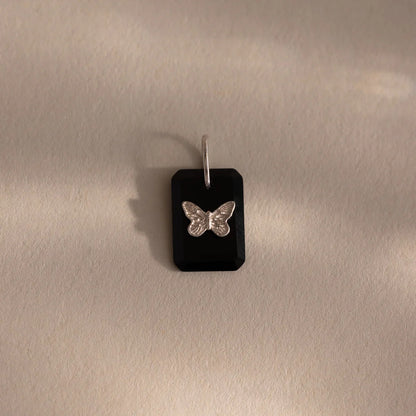 Butterfly pendant on a black card against a beige background