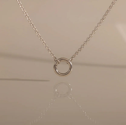 Silver necklace with a circular pendant on a beige background