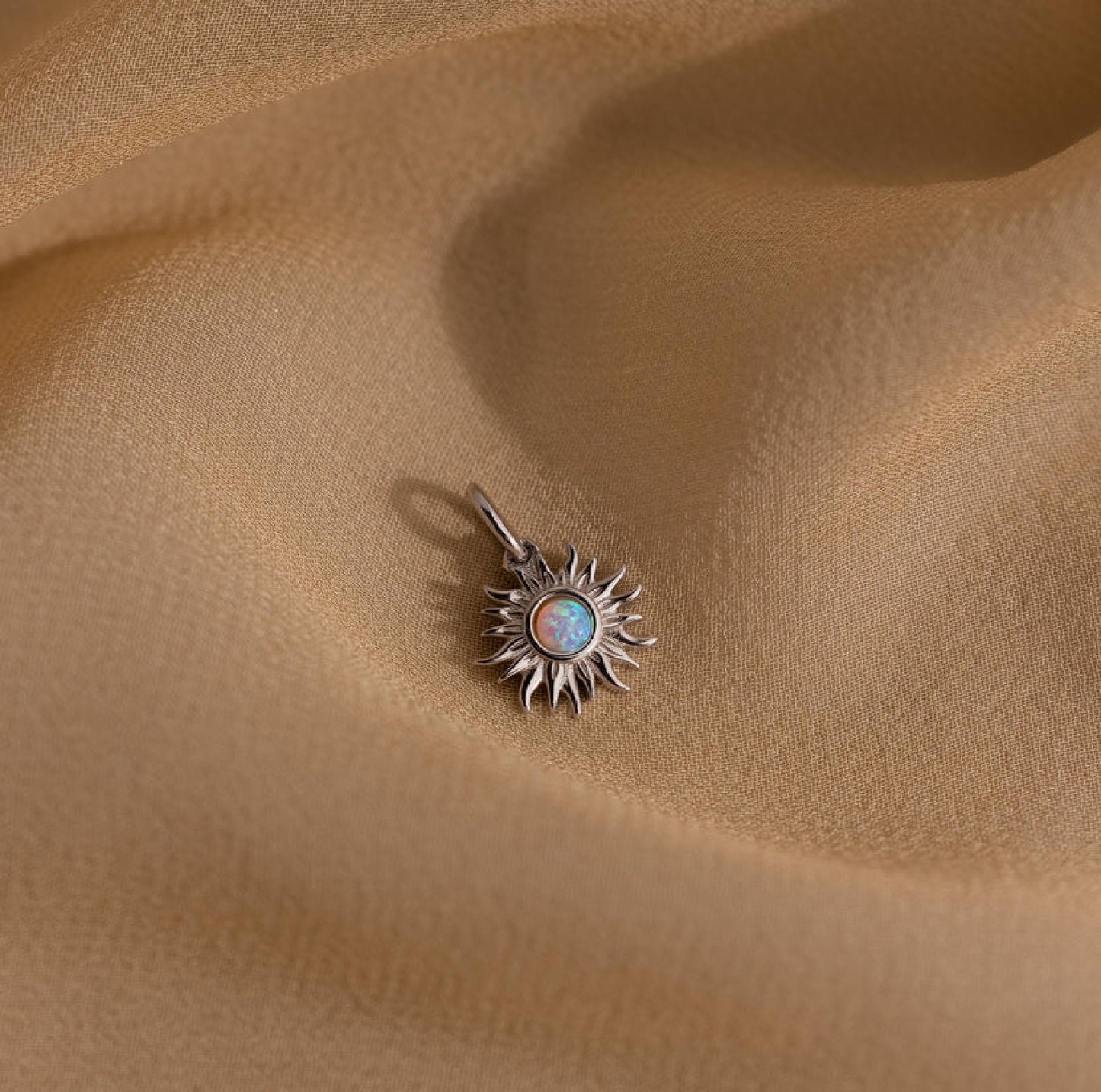 Sun-shaped pendant with a central gemstone on beige fabric