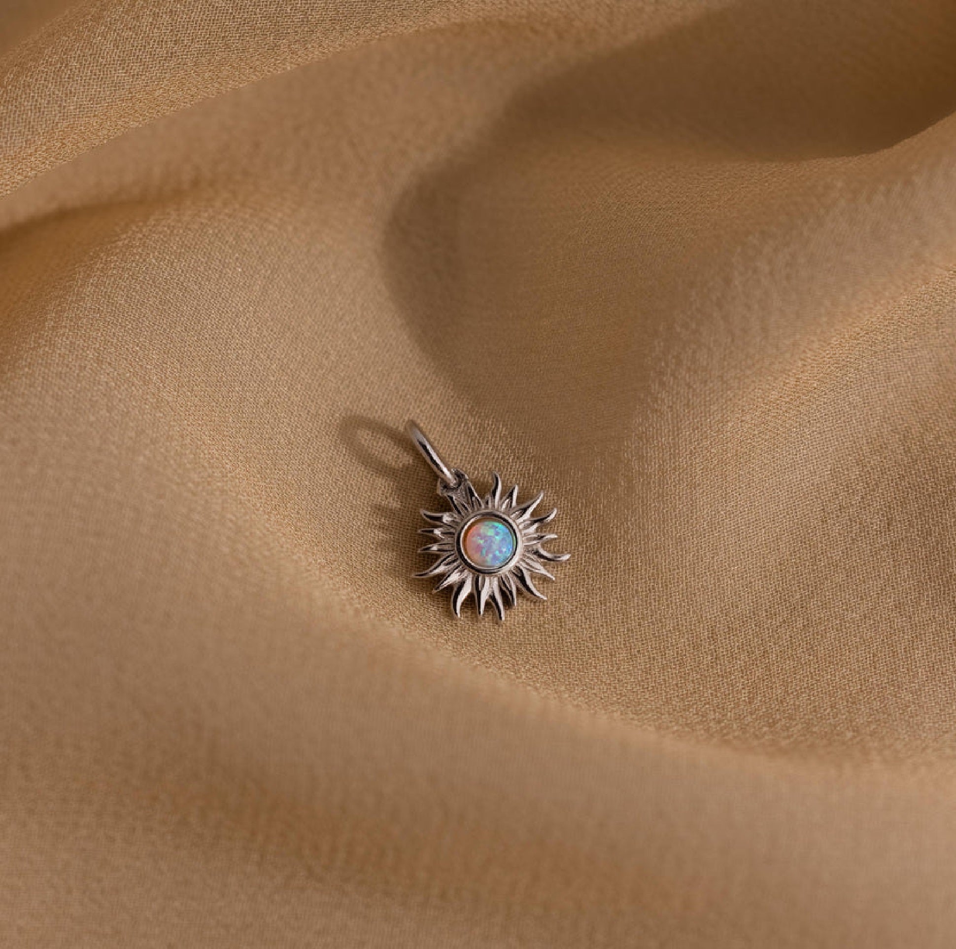 Sun-shaped pendant with a central gemstone on beige fabric