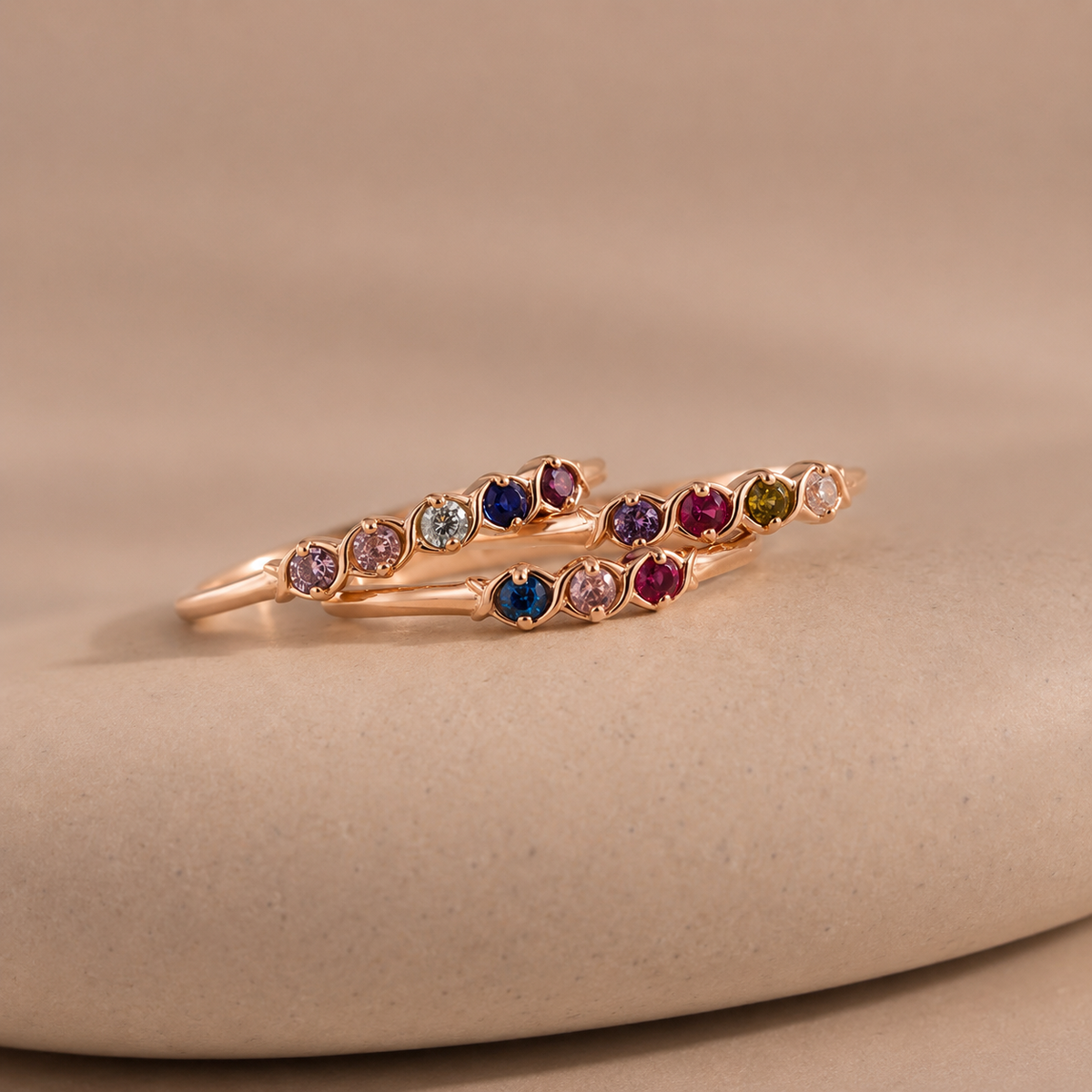 Rose gold ring with multicolored gemstones on a beige background