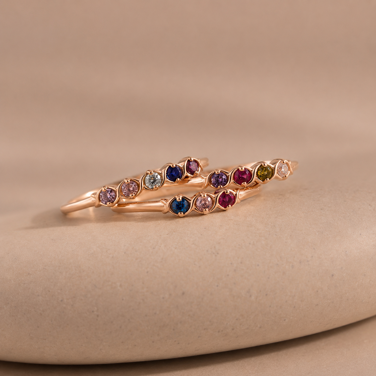 Rose gold ring with multicolored gemstones on a beige background